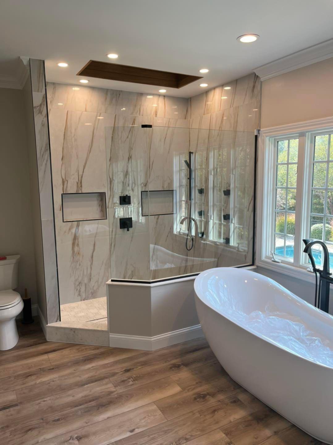Bright bath with freestanding tub, glass shower, and marble finishes